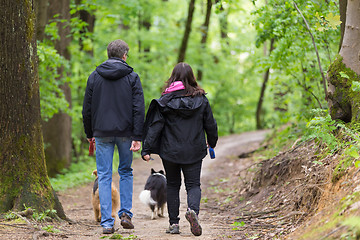 Image showing Couple walking their two dogs in forest