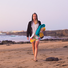 Image showing Sporty woman walking on sandy beach in sunset.