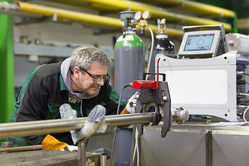 Image showing Industrial worker setting orbital welding machine.