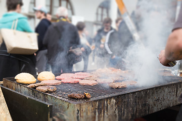 Image showing Beef burgers being grilled on food stall grill.