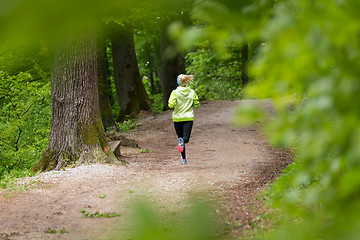 Image showing Sporty young female runner in the forest. 