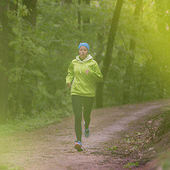 Image showing Sporty young female runner in the forest. 