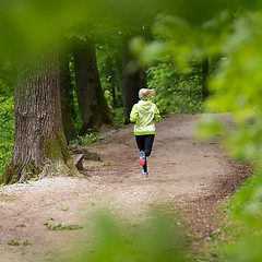 Image showing Sporty young female runner in the forest. 