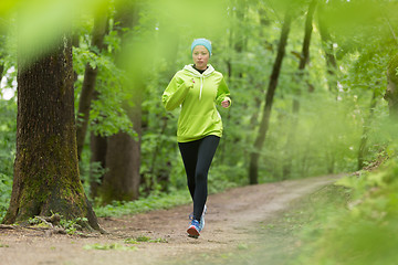 Image showing Sporty young female runner in the forest. 