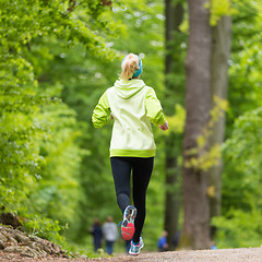 Image showing Sporty young female runner in the forest. 