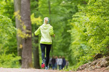 Image showing Sporty young female runner in the forest. 