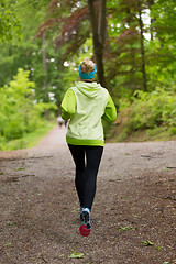 Image showing Sporty young female runner in the forest. 