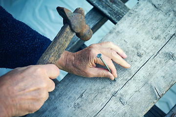 Image showing Closeup of mature man hands nails with old hammer 