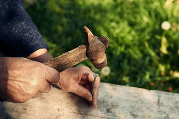 Image showing Closeup of mature man hands nails with old hammer 
