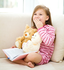 Image showing Little girl is reading a book for her teddy bears