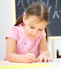 Image showing Little girl is writing using a pen
