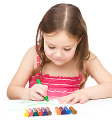 Image showing Little girl is drawing using colorful crayons