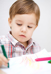 Image showing Little boy is drawing on white paper