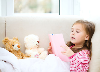 Image showing Little girl is reading a story for her teddy bears