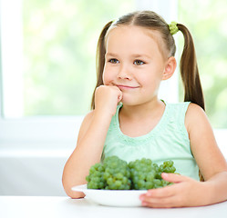 Image showing Cute little girl is eating green grapes