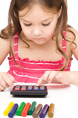 Image showing Little girl is playing with calculator