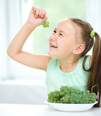 Image showing Cute little girl is looking at green grapes