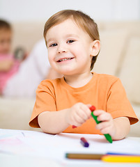 Image showing Little boy is drawing on white paper