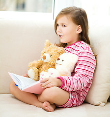 Image showing Little girl is reading a story for her teddy bears