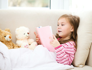 Image showing Little girl is reading a book for her teddy bears
