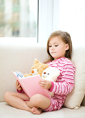 Image showing Little girl is reading a story for her teddy bears