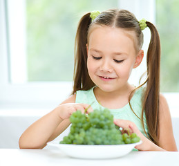 Image showing Cute little girl is eating green grapes