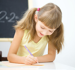 Image showing Little girl is writing using a pen