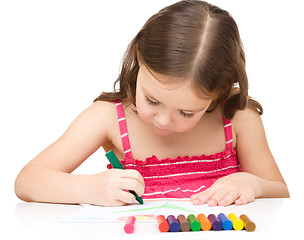 Image showing Little girl is drawing using a crayon