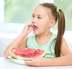 Image showing Cute little girl is eating watermelon