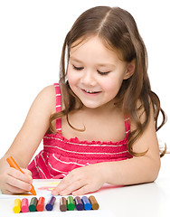 Image showing Little girl is drawing using colorful crayons