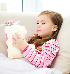 Image showing Little girl is combing her teddy bear