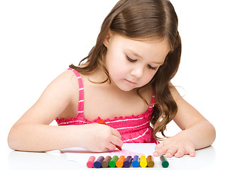 Image showing Little girl is drawing using a crayon