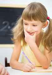 Image showing Little girl is writing using a pen