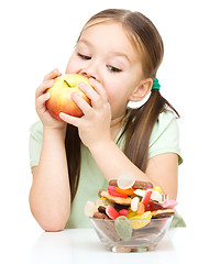 Image showing Little girl choosing between apples and sweets