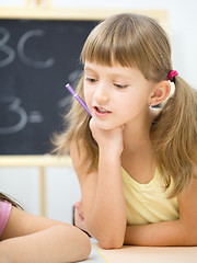 Image showing Little girl is writing using a pen