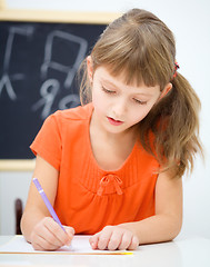 Image showing Little girl is writing using a pen