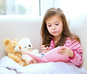 Image showing Little girl is reading a story for her teddy bears