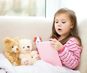 Image showing Little girl is reading a story for her teddy bears