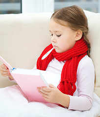 Image showing Ill little girl with thermometer is reading book