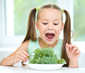 Image showing Cute little girl is eating green grapes