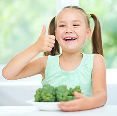 Image showing Cute little girl is eating green grapes