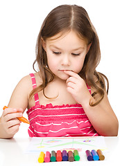 Image showing Little girl is drawing using colorful crayons