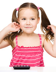 Image showing Little girl is using calculator