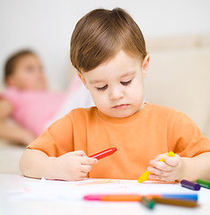 Image showing Little boy is drawing on white paper