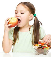 Image showing Little girl choosing between apples and sweets