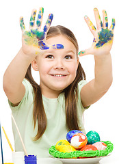 Image showing Little girl is painting eggs preparing for Easter