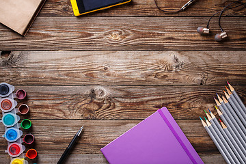 Image showing Watercolors, color pencils and sketchbook on wooden table. Flat lay photo with empty space for logo, text.