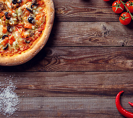 Image showing Italian pizza with tomatoes on a wooden table, top view.