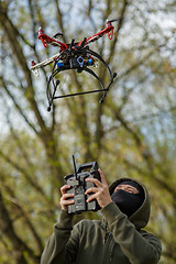 Image showing Man in mask operating a drone with remote control.