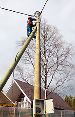 Image showing Electrician connects wires on a pole in a country house